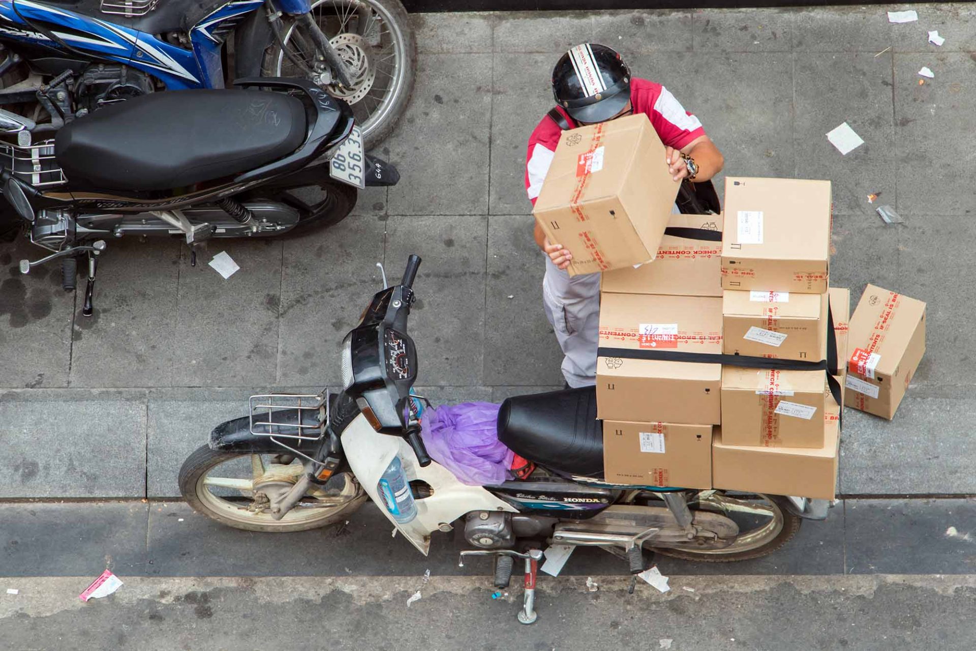 SAIGON, VIETNAM, DEC 13 2017, Delivery Of Consignments On Motorbike. Motorcyclist With The Many Packet On Motorcycle At Street Saigon City, Vietnam.